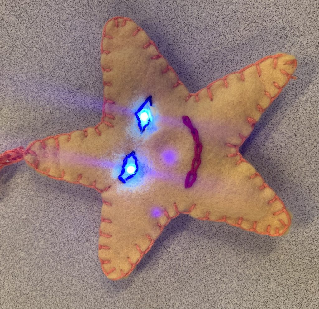 Billede af en håndsyet stjerne med lys i øjnene.