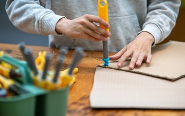 Dreng skruer skrue i pap med makedo-værktøj